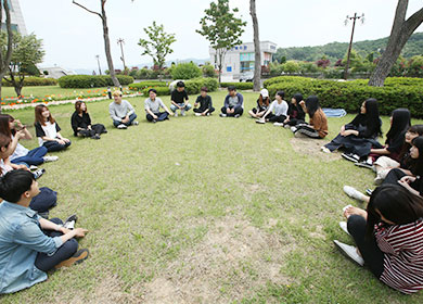 잔디밭 위에 둥글게 둘러 앉은 학과 학생들