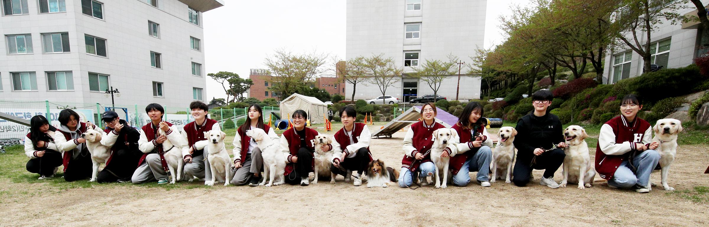 각자의 강아지를 옆에 두고 앉아 정면을 바라보는 학생들 사진