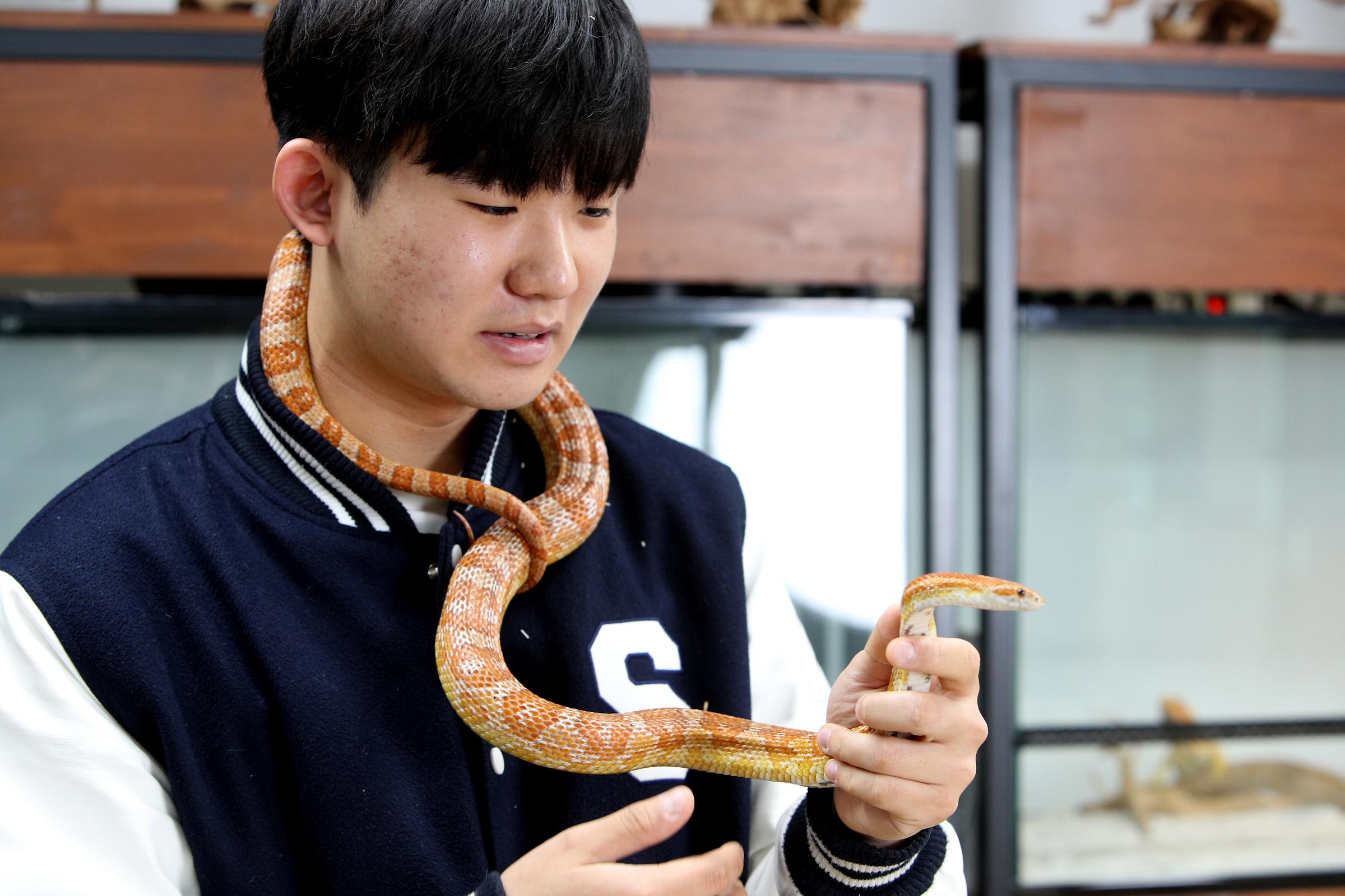 뱀을 목에 두르고 있는 남학생의 사진